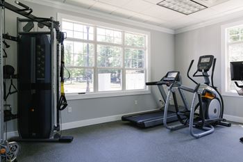 A home gym with a treadmill, elliptical trainer, and a stationary bike.